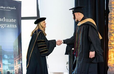 Walker College Dean Sandra Vannoy congratulates a newly hooded student.