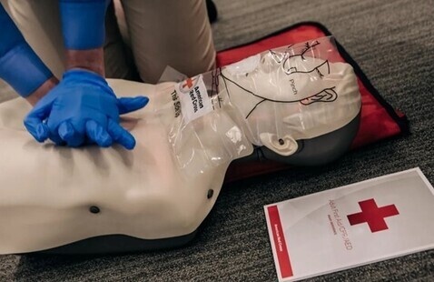 A volunteer doing chest compressions on a dummy
