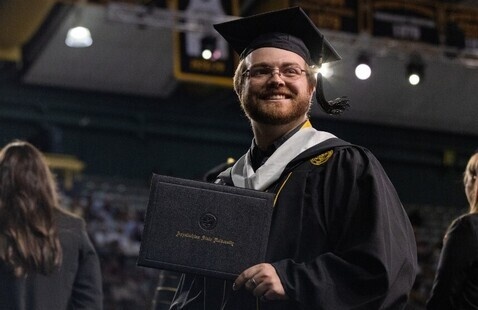 A master's graduate holding their Appalachian State University diploma at a Commencement Ceremony.