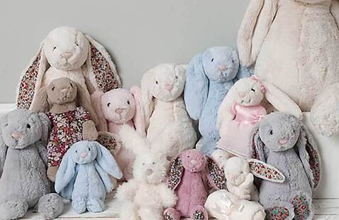 A family of stuffed, plush rabbits, all sitting on a bed.