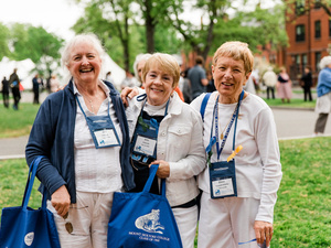 Group of smiling alums pose together at Reunion, some holding reunion swag.