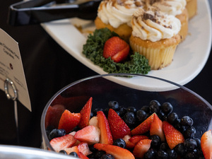 A bowl of berries, vanilla cupcakes in the background.