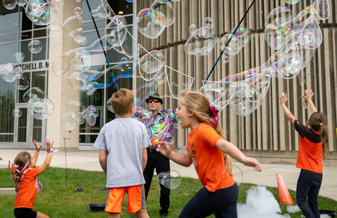 young kids playing outside on a sunny day surrounded by bubbles