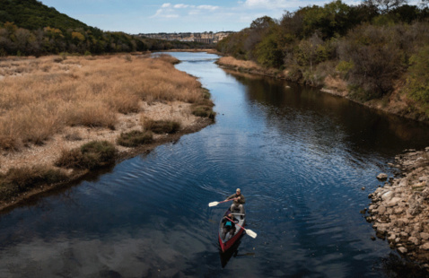 A canoe and the two rowers inside slowly paddle down the Brazos river.