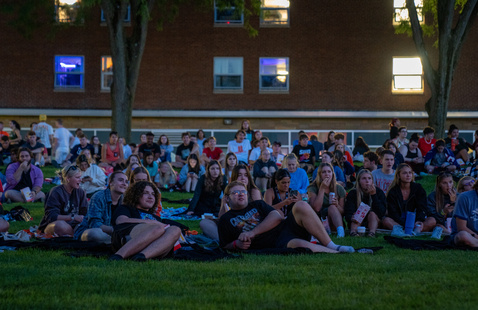 Community members gather around a movie on the Kuhlin center lawn