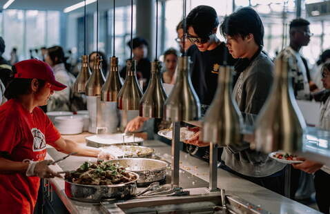 A person serves food to students