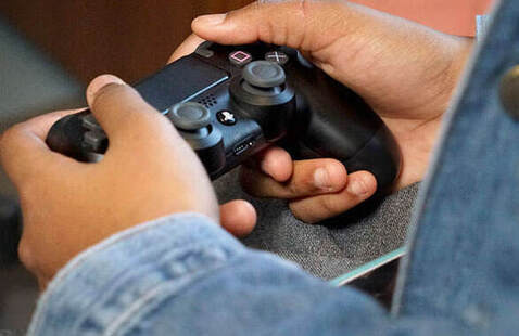 Two hands gripping a Playstation controller in a game-ready manner.