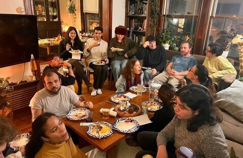 A group of graduate students sitting around a wooden table eating a meal.