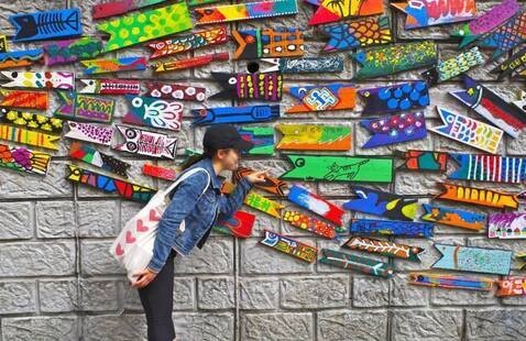 Woman bends over art exhibit of many colorful plaques in South Korea