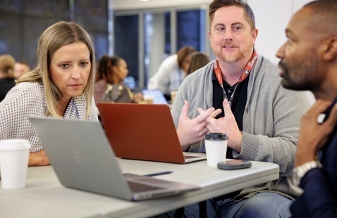 People talking around a laptop