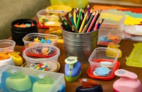 a variety of craft supplies including colored pencils, cut out shapes, and paper