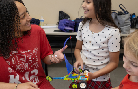 A STEM Summer camp counselor engages with a camper in a STEM activity.