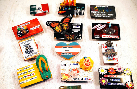 An assortment of artistic magnets with colorful designs and social messages on a white background.