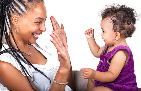 A caregiver sits with a smiling baby