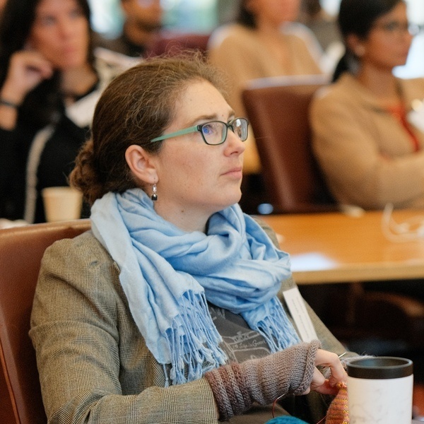 A conference attendee focusing on the speaker, who is not in frame