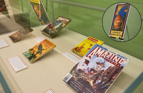 One of two exhibit cases that feature past issues of "Amazing Stories'. In the Top right is a circular photo of the exhibit poster.