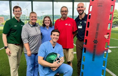 Athletic trainers and physicians gather in a group on the sideline
