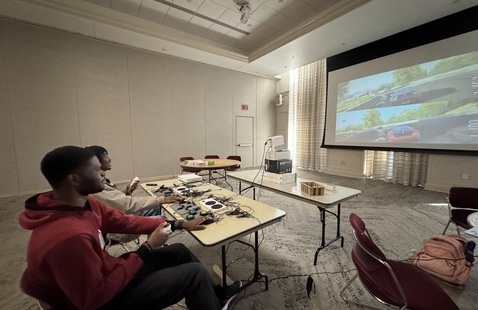 Two students play a racing game with adaptive controllers 