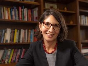Cristina Alcade is facing the camera with books behind her
