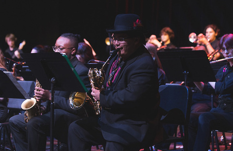 A jazz band performs on stage, with a focus on saxophone players in the foreground.