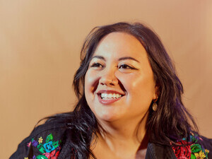  Headshot of Christian Aldana, the speaker, with a black shirt with colorful floral designs.