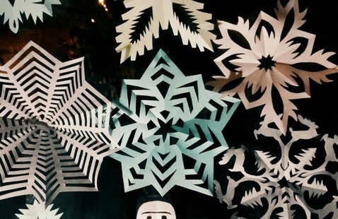 Pastel colored paper snowflake cutouts scattered on a black background