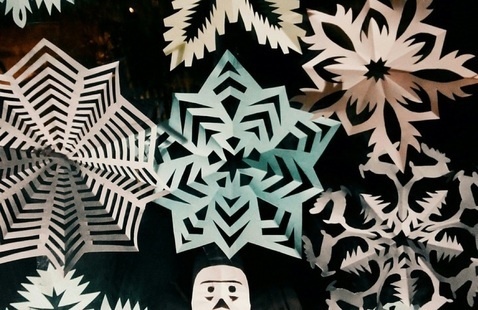 Pastel colored paper snowflake cutouts scattered on a black background
