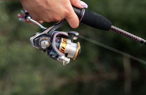 hand holding a fishing rod and zoomed in on the reel