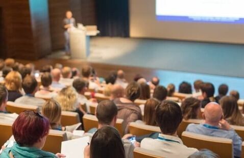 People sitting in a lecture hall watching a speaker