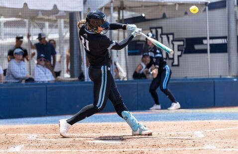 Female softball player at home plate swinging a bat