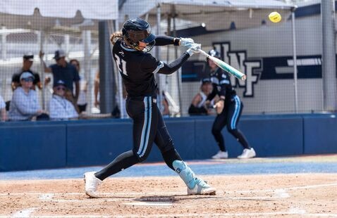 Female softball player at home plate swinging a bat