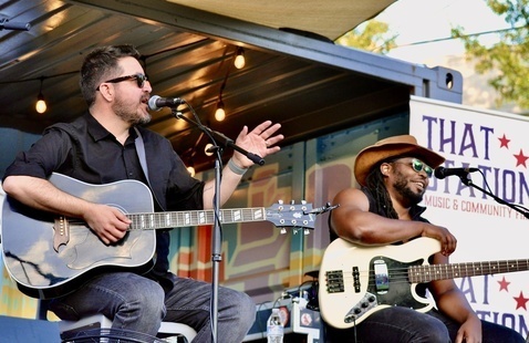 Two musicians with guitars on stage.