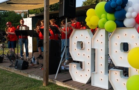 A band wearing red shirts plays on stage next to a large "919" light up sign with balloons