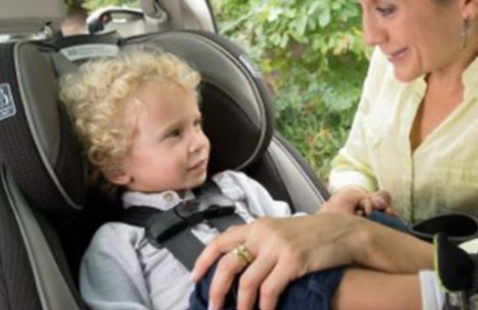 A mother setting up her child in a car seat