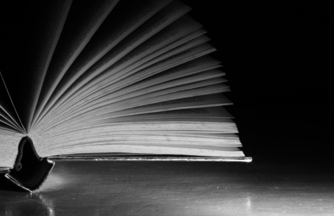 Black and white book with pages fanned open in dramatic lighting 