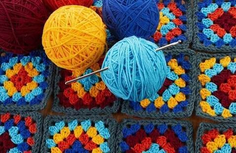 Balls of yarn and crocheted granny squares on a table