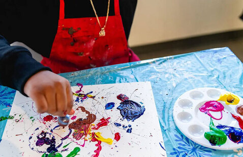 Child wearing red smock painting