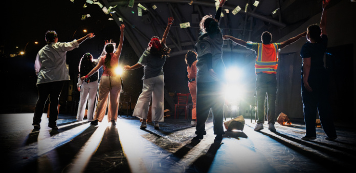 dancers on stage with arms extended up towards the light
