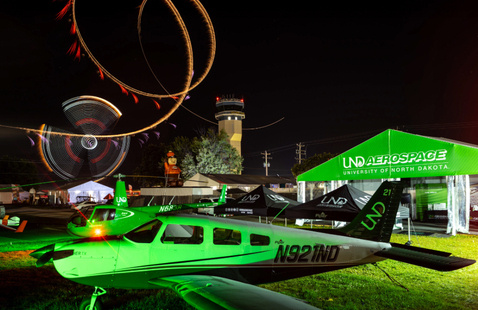 UND Aerospace booth at Oshkosh during the night airshow with fireworks in the background.