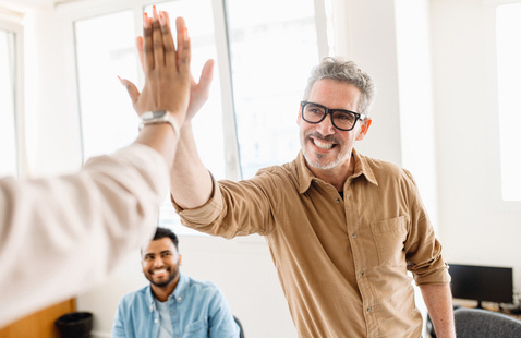 Man high fiving someone out of frame while smiling