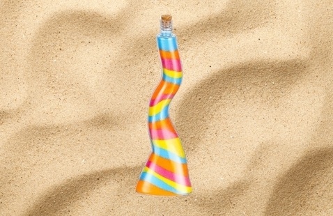 image of a bottle that hs different colored layered sand in it against a sand background.