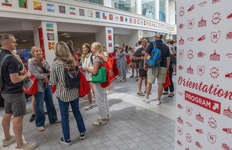 Slant Walk hallway of Armstrong Student Center during the resource fair held daily during orientation - with a group of students and parents and a wayfinding sign indicating Orientation