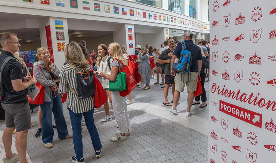 Slant Walk hallway of Armstrong Student Center during the resource fair held daily during orientation - with a group of students and parents and a wayfinding sign indicating Orientation