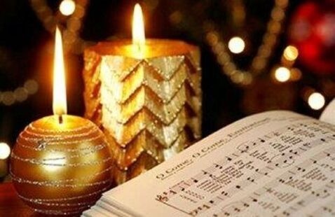 2 lit candles with hymnal showing O Come, All Ye Faithful