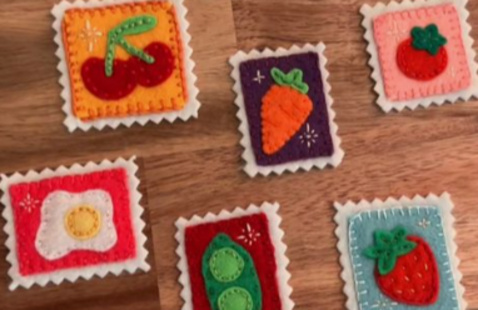 A variety of felt pins, with different foods, plants, and berries on them.