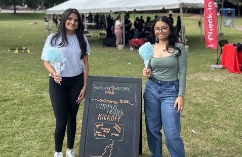 Two people standing by a chalkboard welcoming guests to a Campu Health Kickoff event.