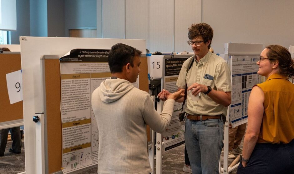 Postdoc presents research posters and is asked questions by PDRD attendees
