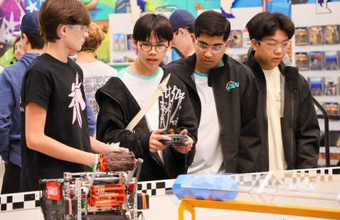 Student competitors standing together, observing robot in action