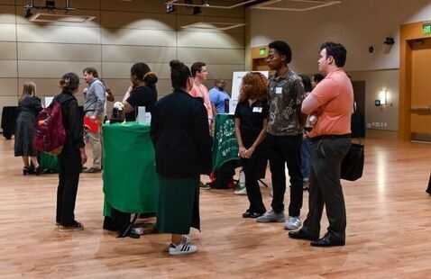 Students and employers speaking in a ballroom at a tabling event.