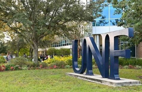 Large blue UNF letters standing upright on grass